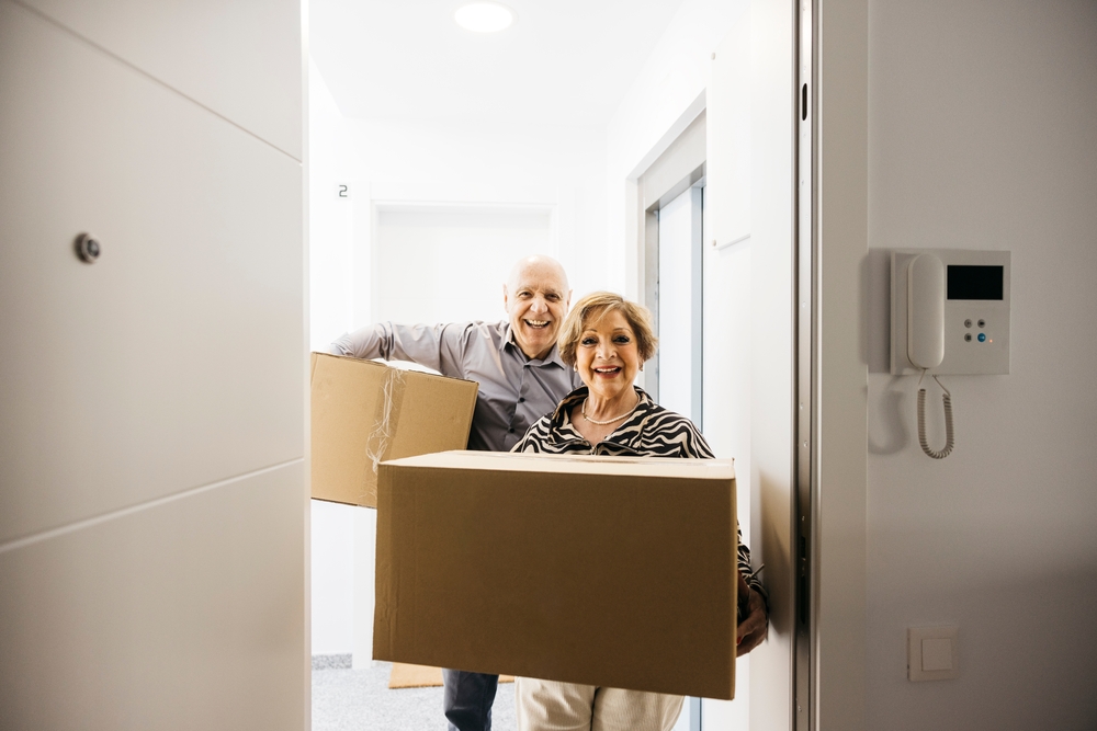Smiling,Senior,Couple,Carrying,Cardboard,Boxes,While,Entering,Their,New
