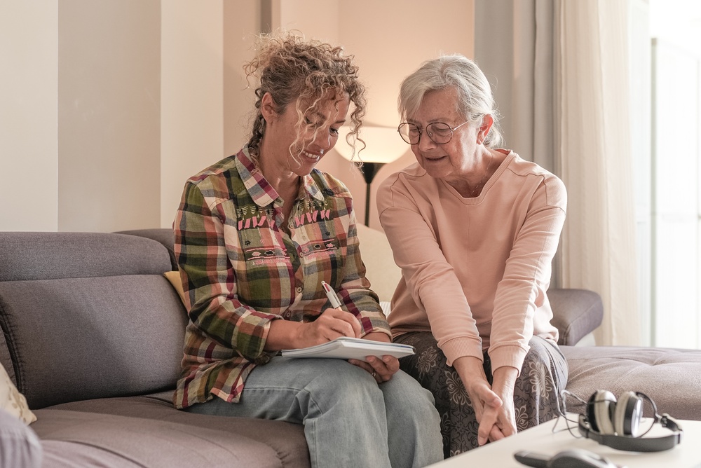 Smiling,Senior,Woman,And,Caregiver,Sharing,A,Moment,Sitting,Together