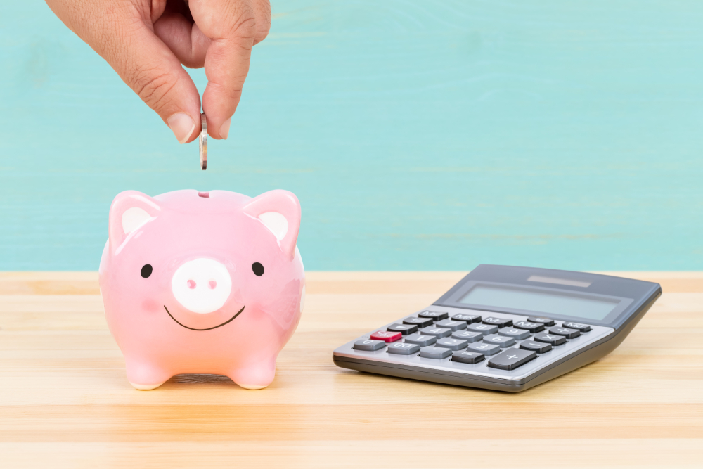 Piggy,Bank,With,Hand,Putting,Insert,Coin,And,Calculator,,On